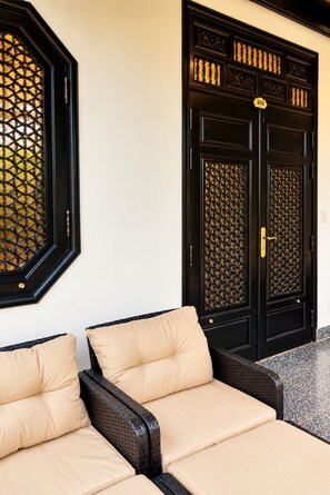 Entrada d'un hotel amb dues portes negres, cada una amb una placa numerada, i una zona de seients amb coixins beix.