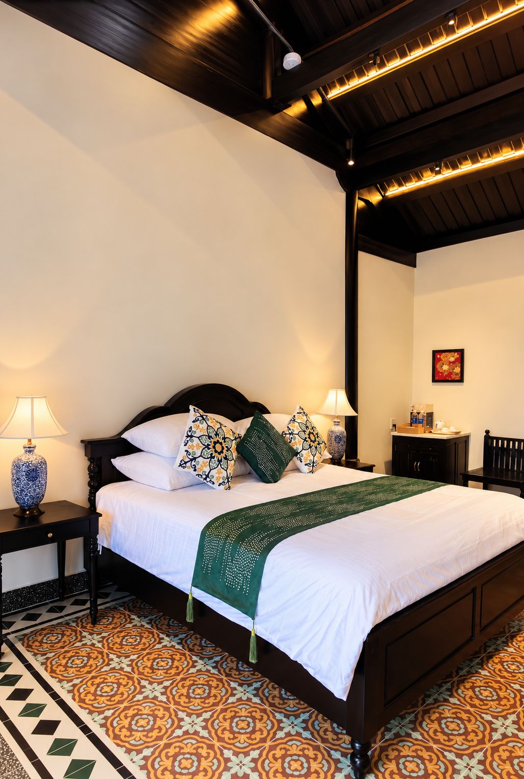 Cama bem arrumada com almofadas estampadas, manta verde e mesa de cabeceira com abajur.