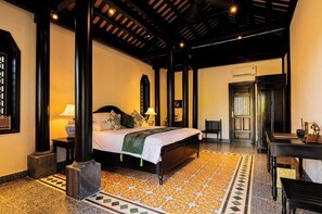 Quarto de hotel com uma cama, uma escrivaninha e uma cadeira.