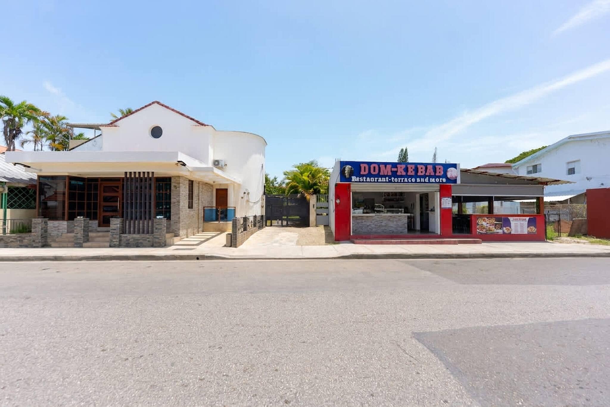 Une vue de rue avec un immeuble moderne à deux étages et un petit kiosque à nourriture.