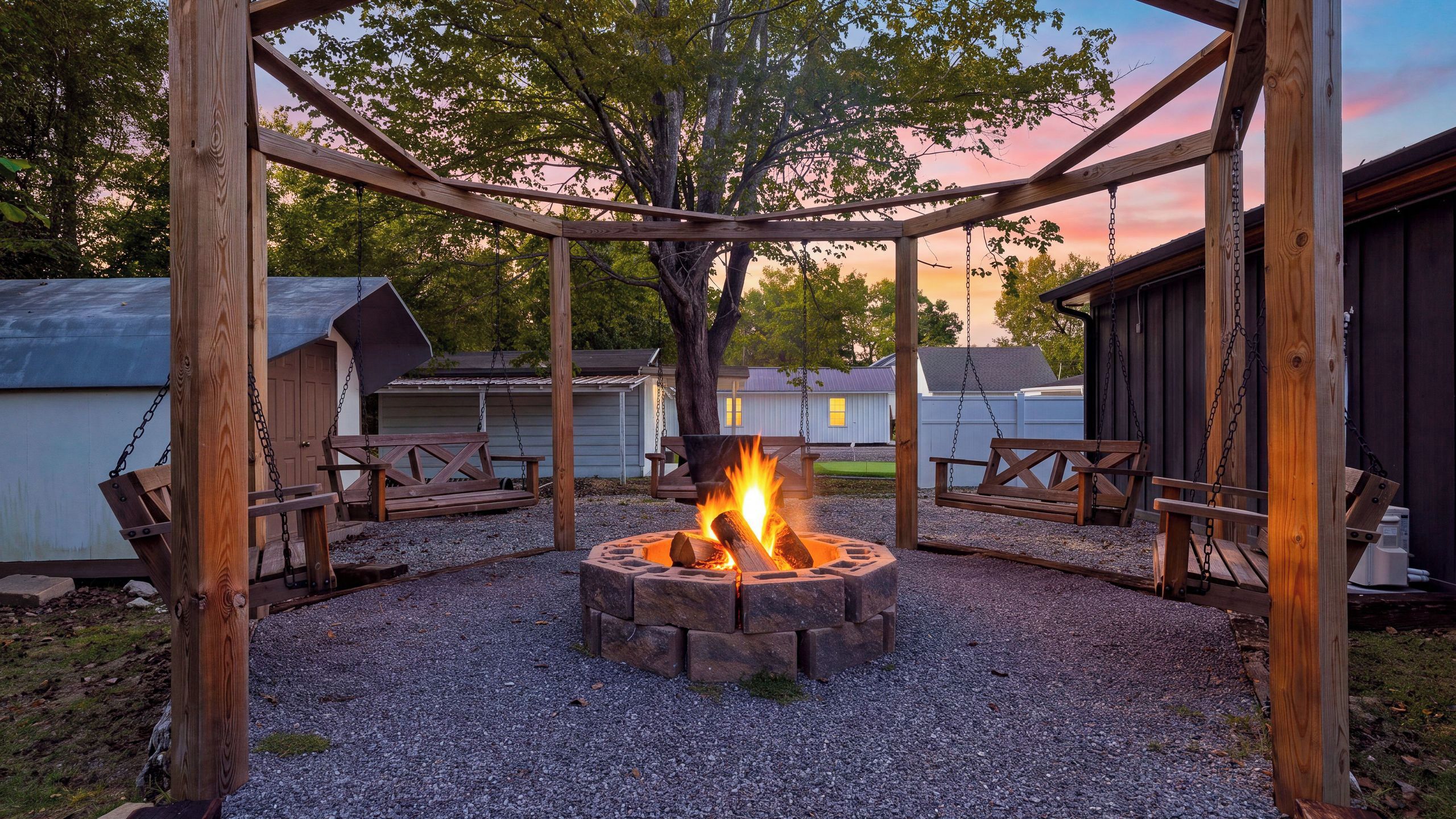 A fire pit surrounded by wooden benches and a pergola structure.