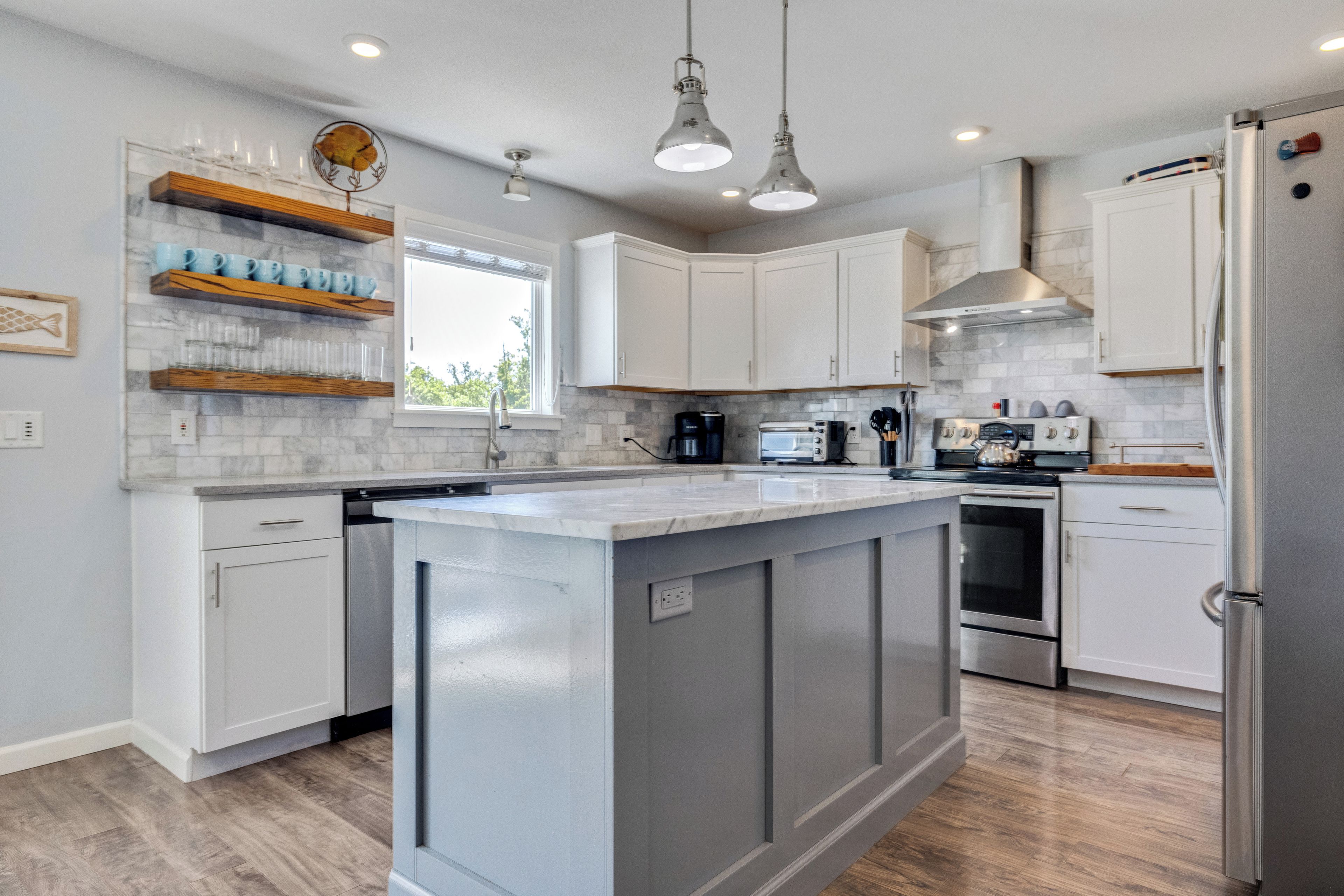 Una cocina moderna con armarios blancos, una isla central y electrodomésticos de acero inoxidable.