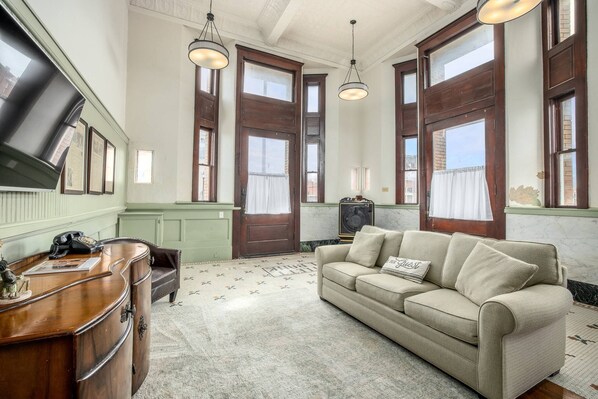 A room with a wooden desk, a beige sofa, and a patterned carpet.