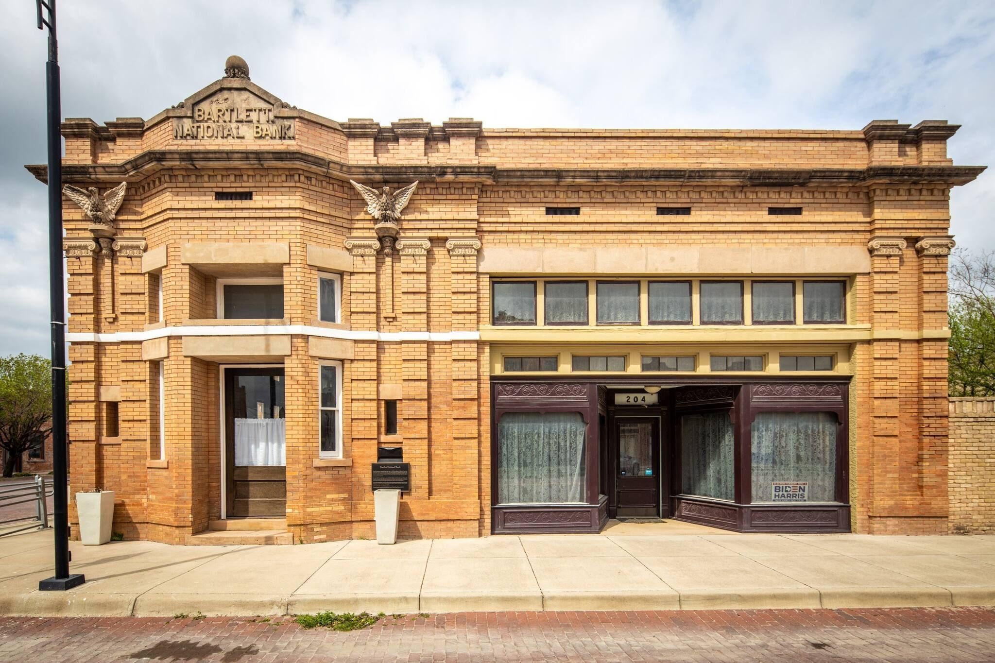 A historic building with a prominent entrance, a plaque, and a sign indicating a business.