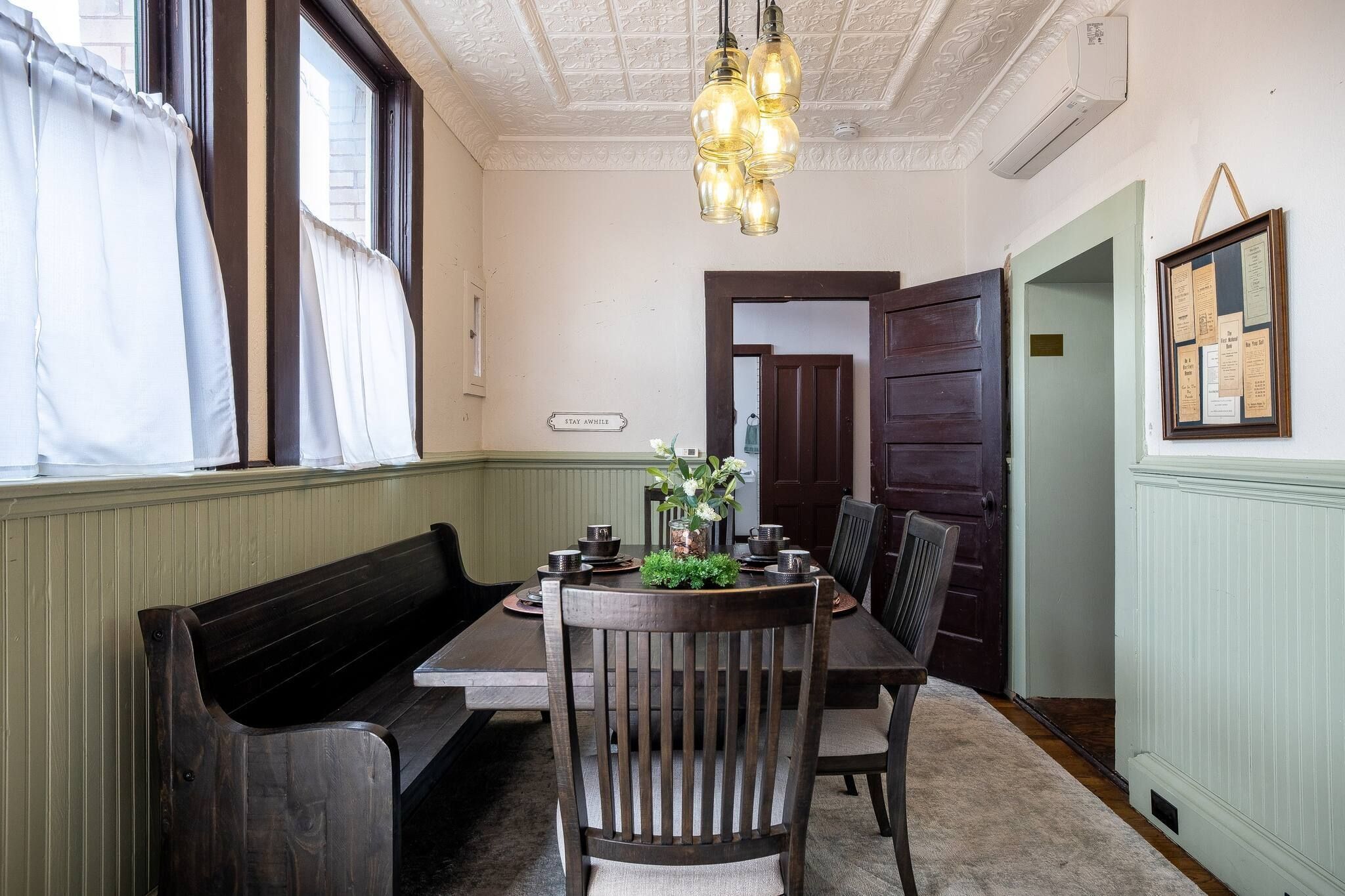 A dining area with a wooden table, chairs, a bench, and a hanging light fixture.