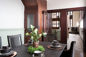 A dining area with a wooden table set for four, a vase with flowers, and a coin jar centerpiece.