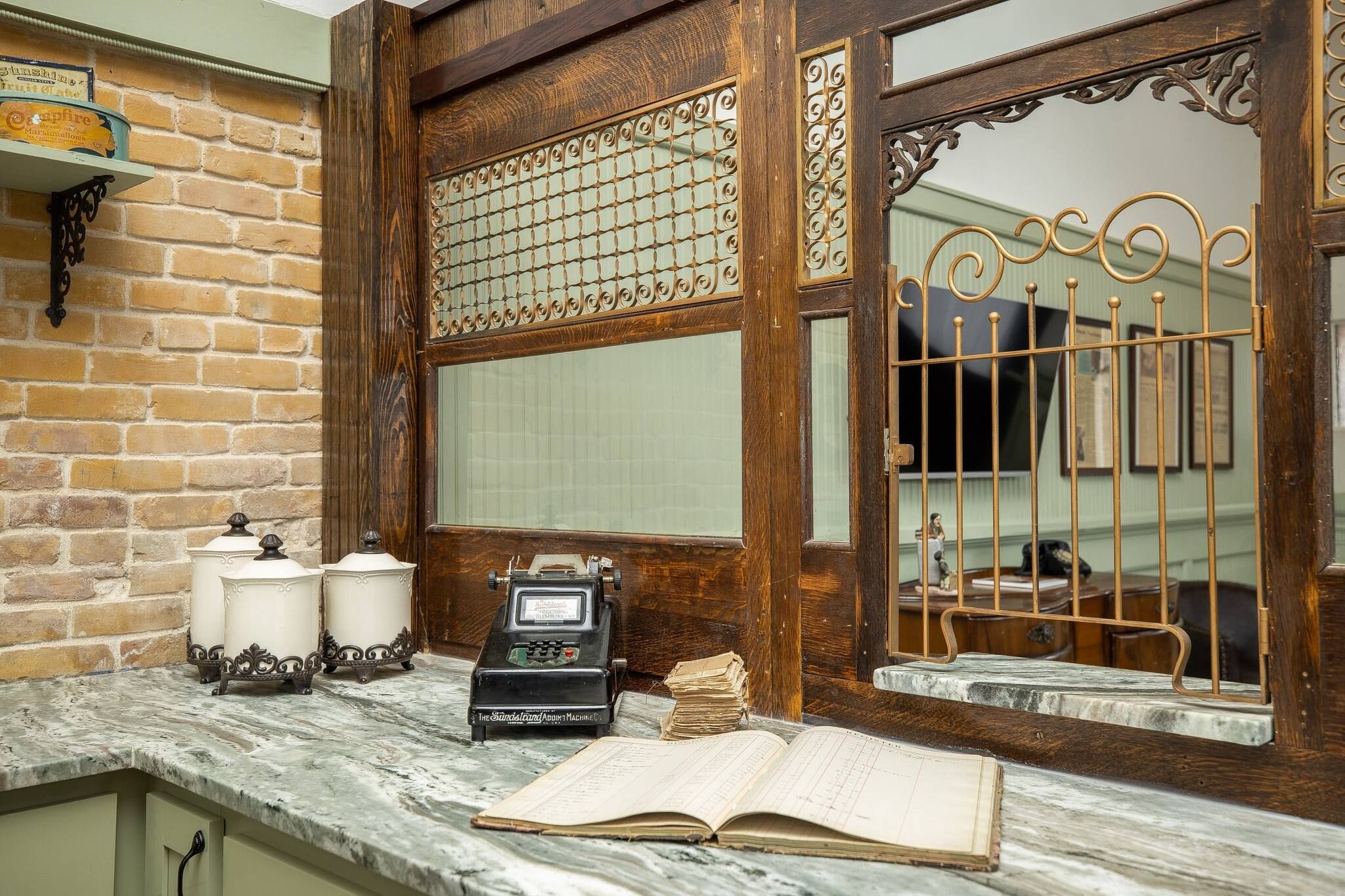 A vintage kitchen with a marble countertop, a typewriter, and a large window with a decorative metal grille.