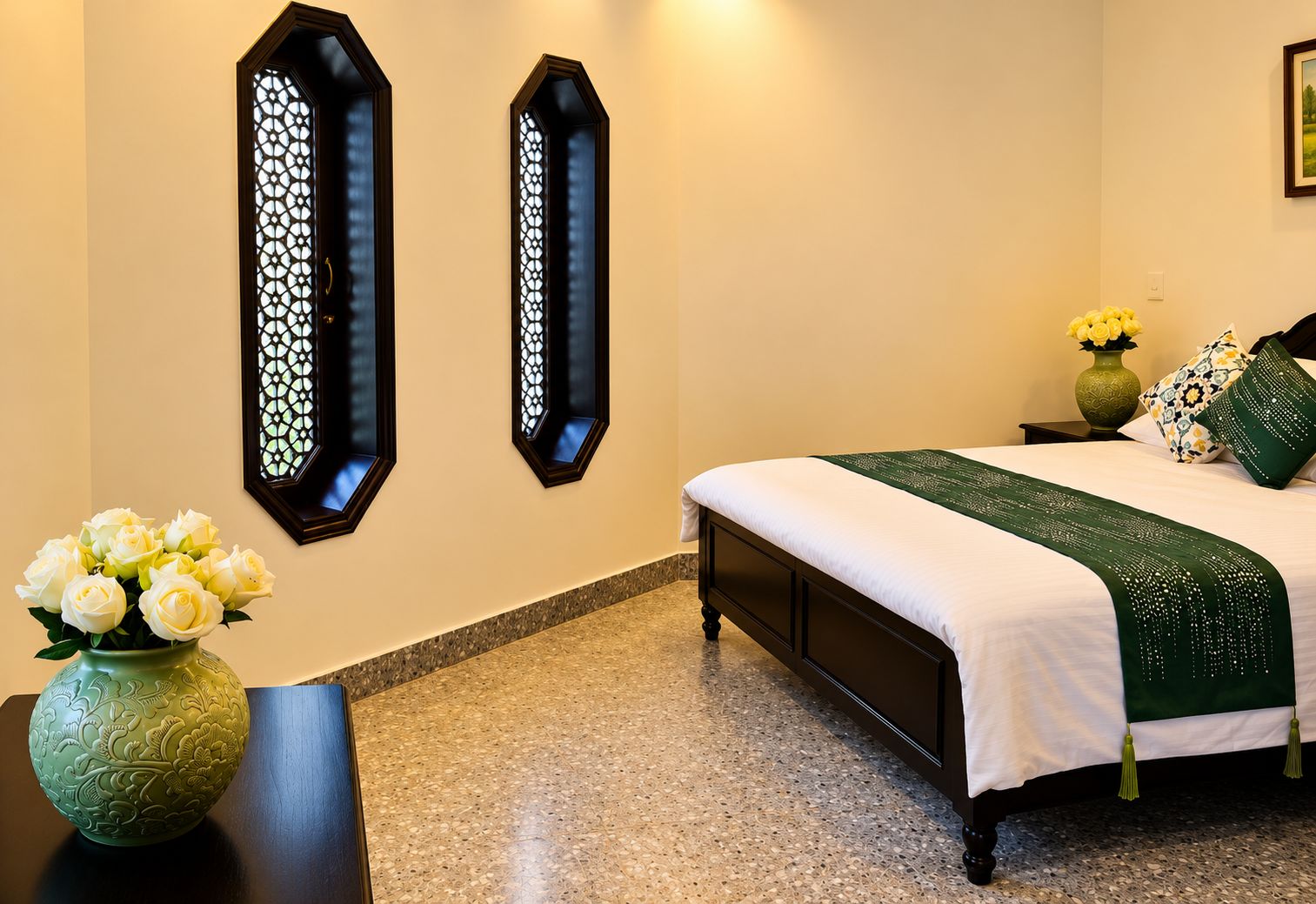 A hotel room with a bed, a decorative wall panel, a vase with flowers, and a nightstand.
