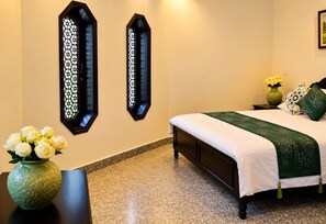 Una habitación de hotel con una cama, un panel decorativo en la pared, un jarrón con flores y una mesita de noche.