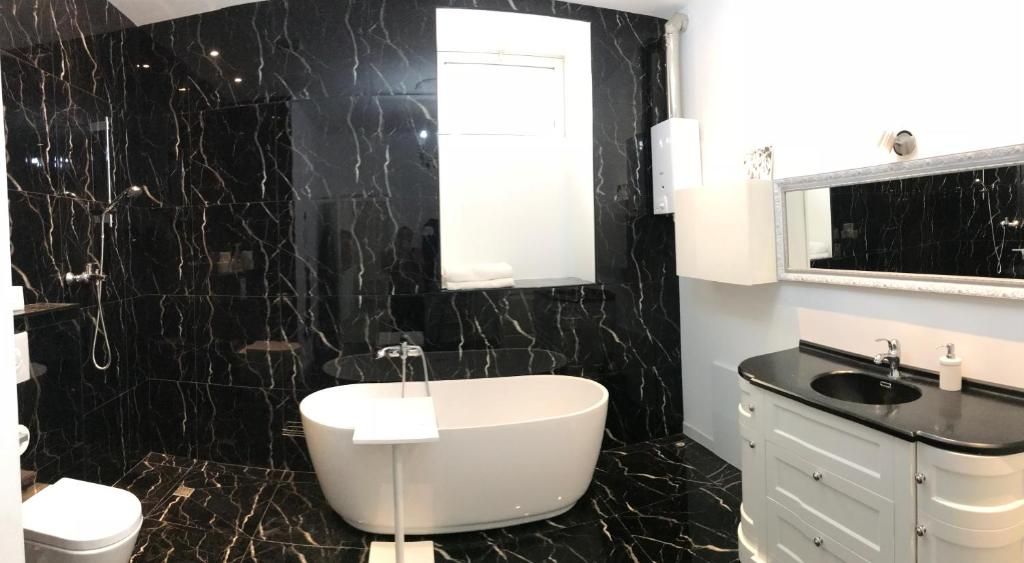 Un baño moderno con una bañera independiente, un tocador con lavamanos y un espejo grande.