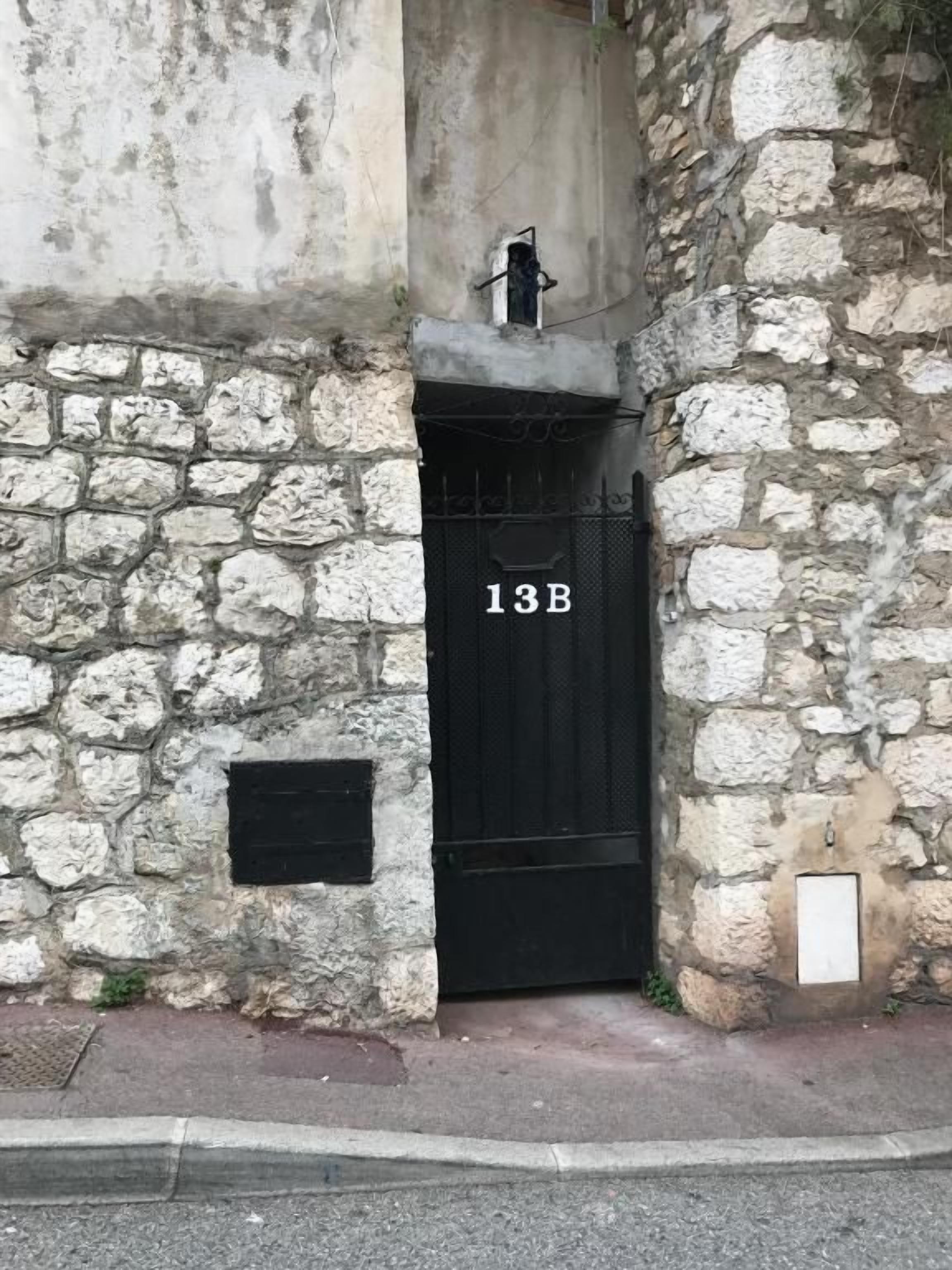 A stone building with a black door marked '13B'.