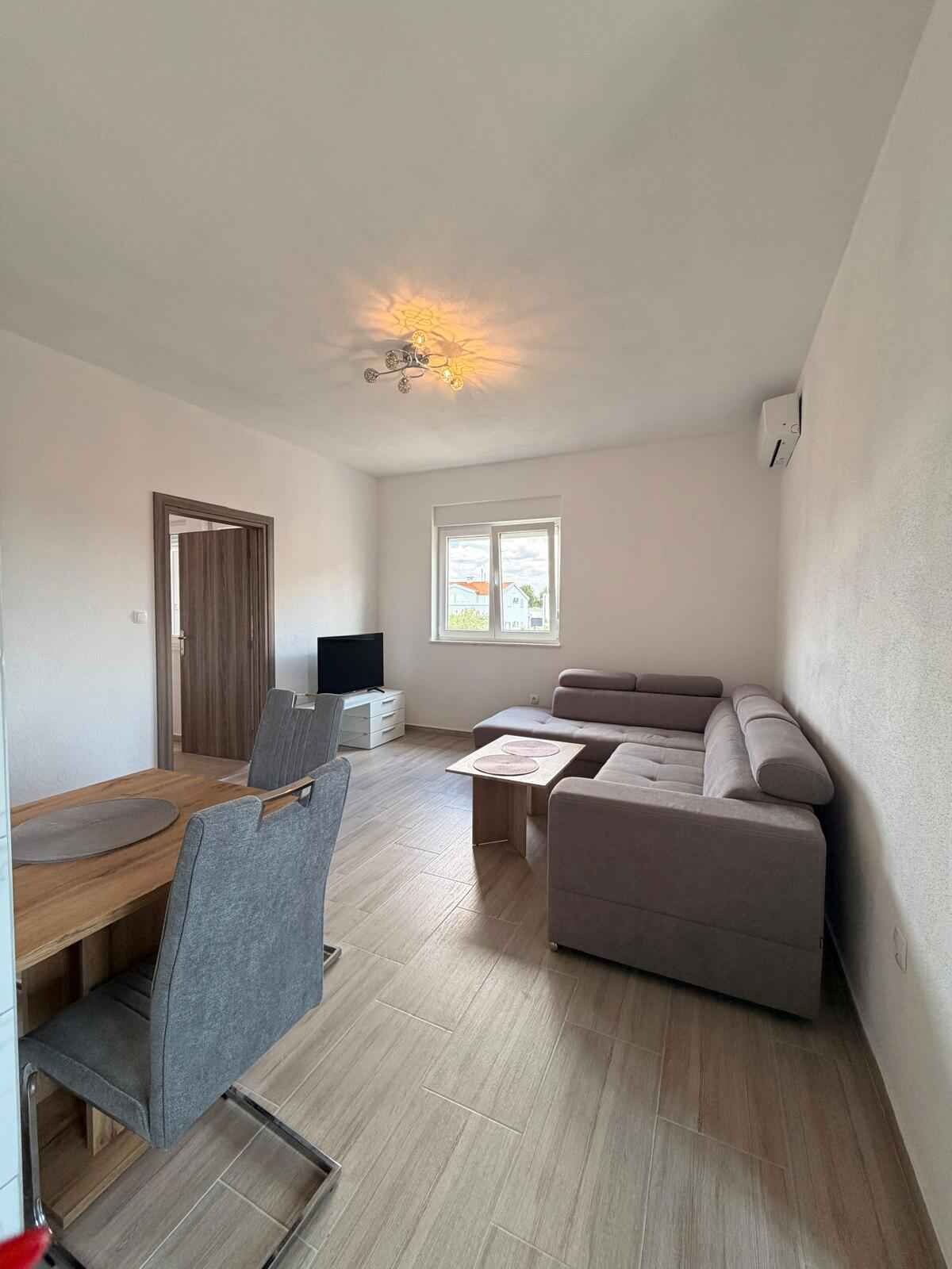 A spacious living area with a sofa, a dining table with chairs, and a television.