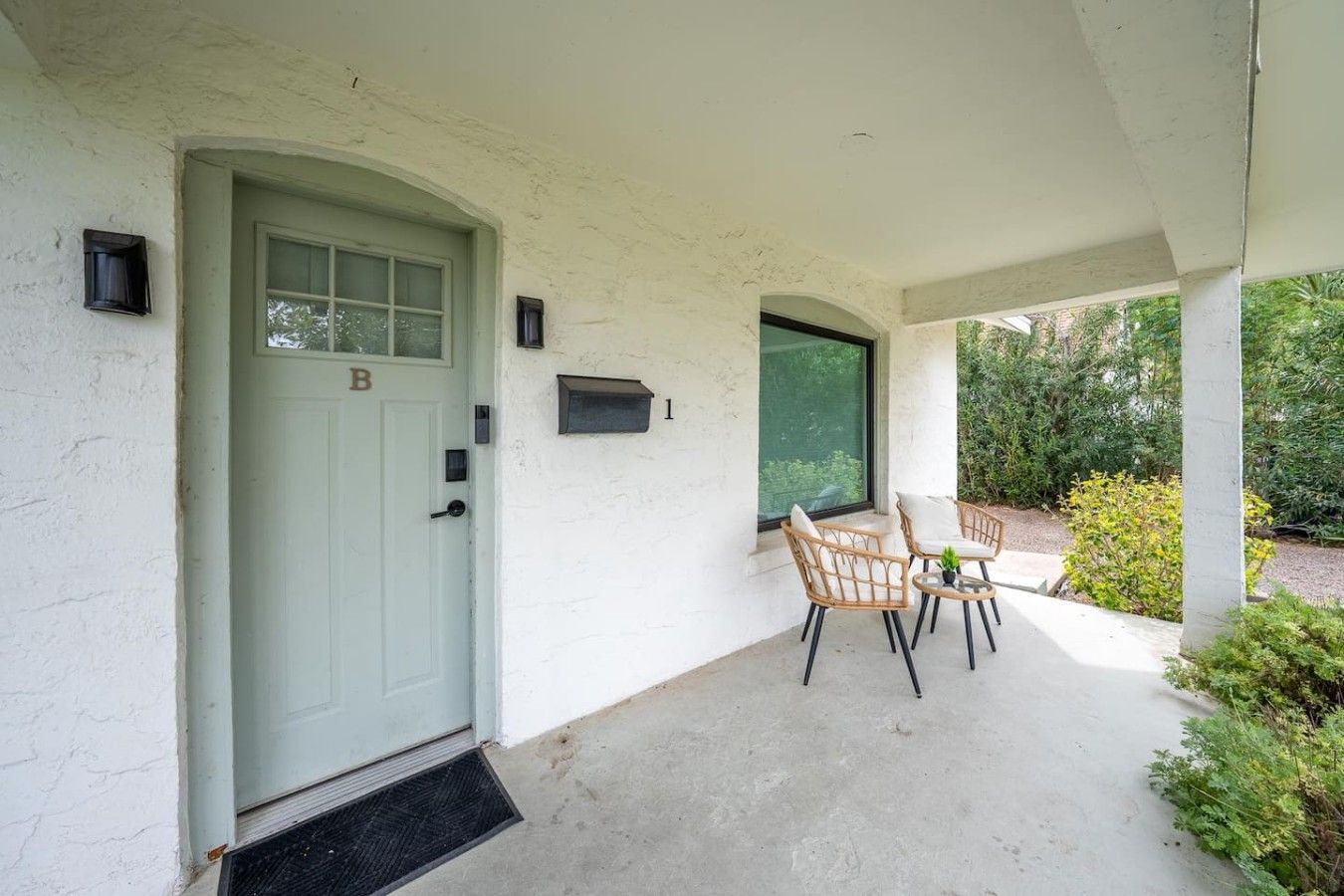 A covered porch with a door marked 'B', two wicker chairs, and a small table.