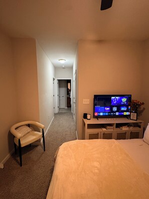 Ein Hotelzimmer mit einem Bett, einem Sessel, einem Fernseher und einem Schreibtisch mit einem Computer.