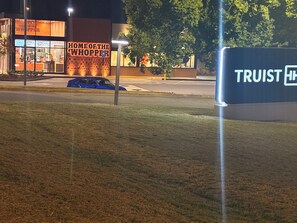 Un bâtiment sur lequel on peut lire l’inscription « ICI, VOUS TROUVEZ LE WHOPPER », avec une voiture bleue garée devant.
