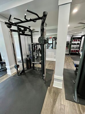 Ein Fitnessraum mit Trainingsgeräten, einem Gewichtständer und einem Spiegel.