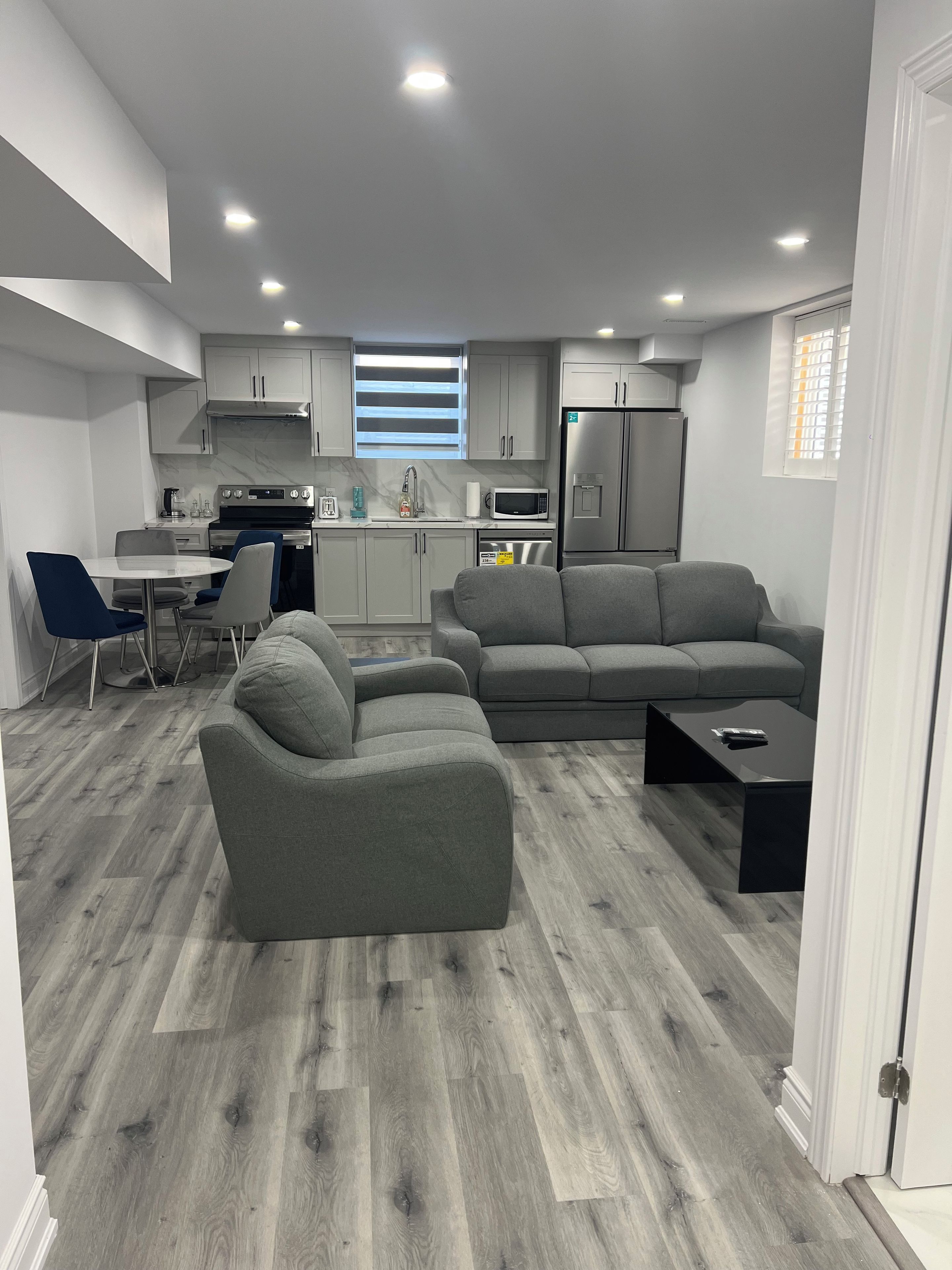A modern kitchen with grey cabinets, a built-in microwave, and a stainless steel refrigerator.