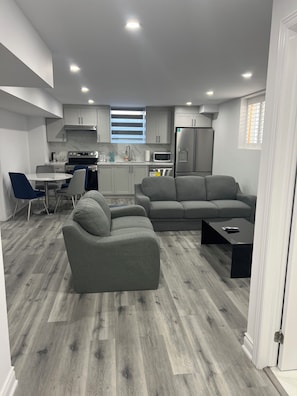 A modern kitchen with grey cabinets, a built-in microwave, and a stainless steel refrigerator. - Welcome to Skies Abode. (Brant)