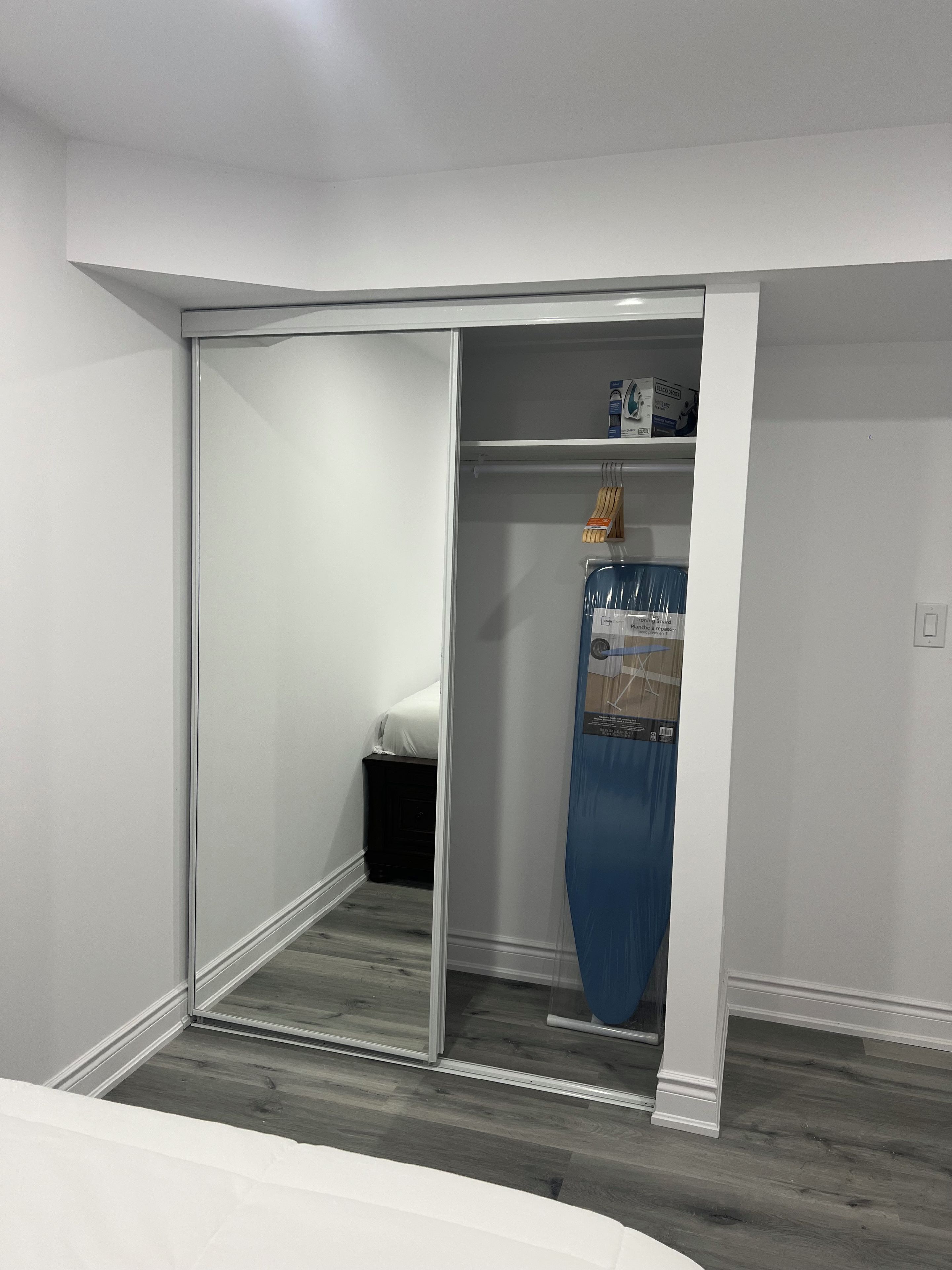 A room with a sliding door closet, a bed, and a blue curtain.