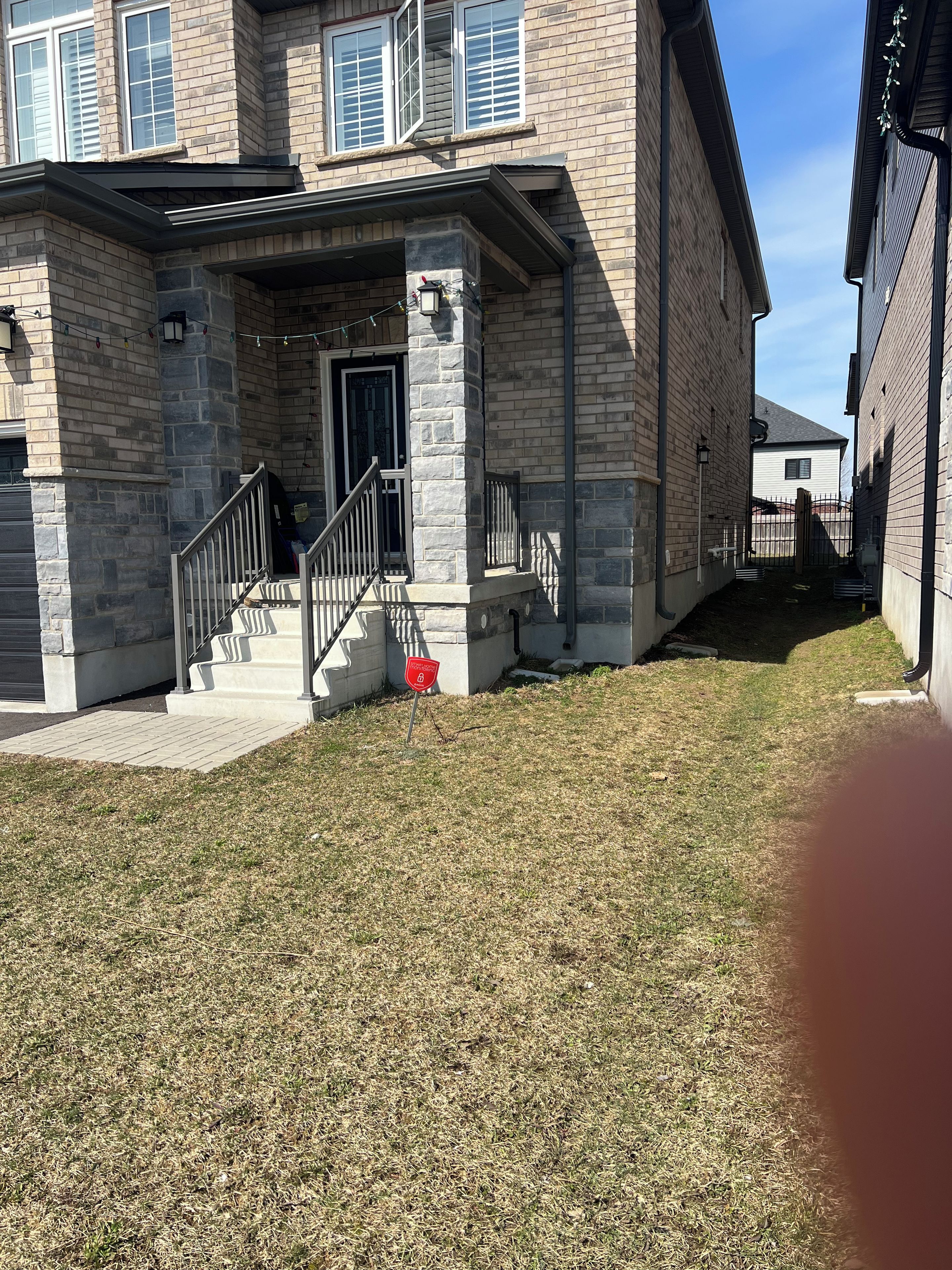 A residential building with a stone facade, a front porch, and a gated entrance.