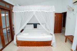 A bed with a canopy, a wooden headboard, and a bedside table with a lamp.