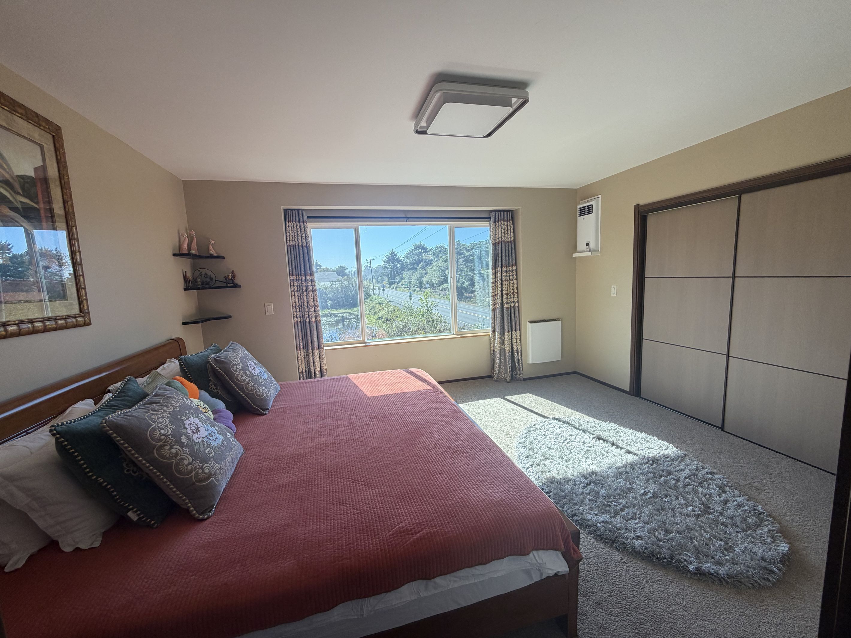 A bedroom with a bed, a window, a radiator, and a wardrobe.