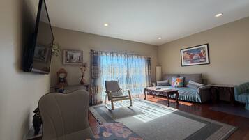 A living room with a sofa, armchairs, a coffee table, and a television.