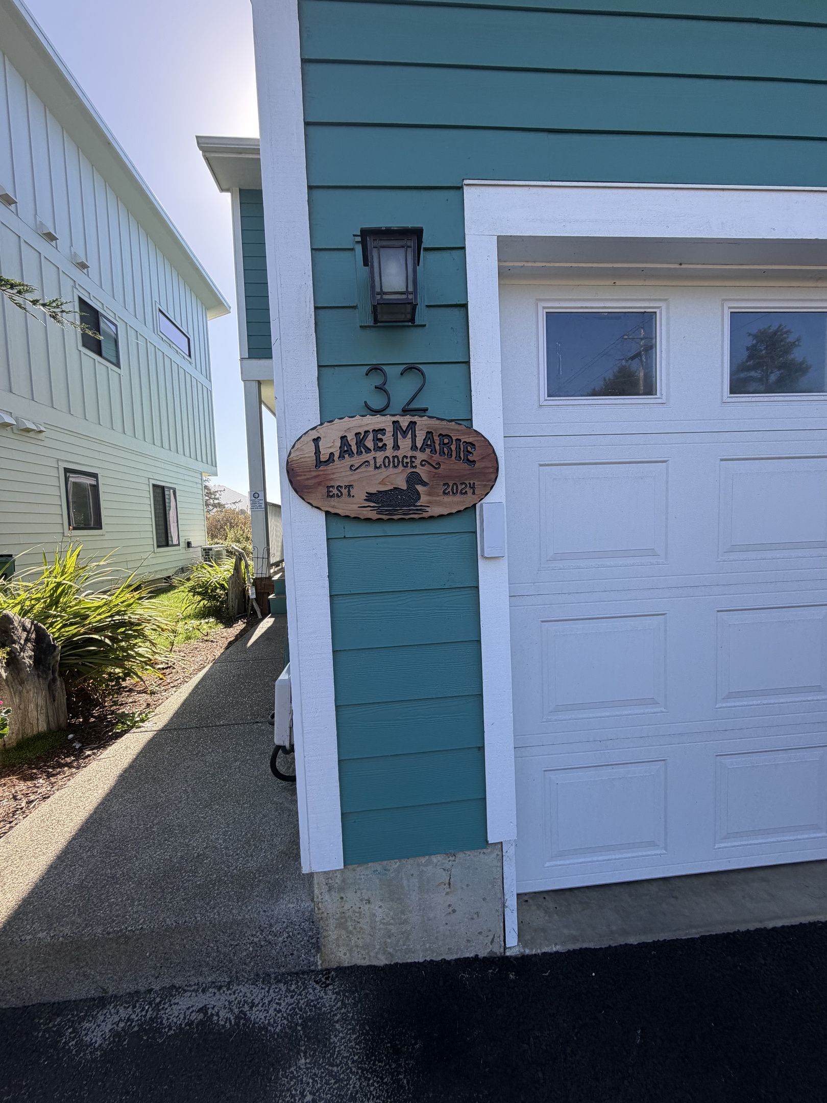 A wooden sign with the text 'Lakesmarie Lodge' and the number '32' on a teal building.