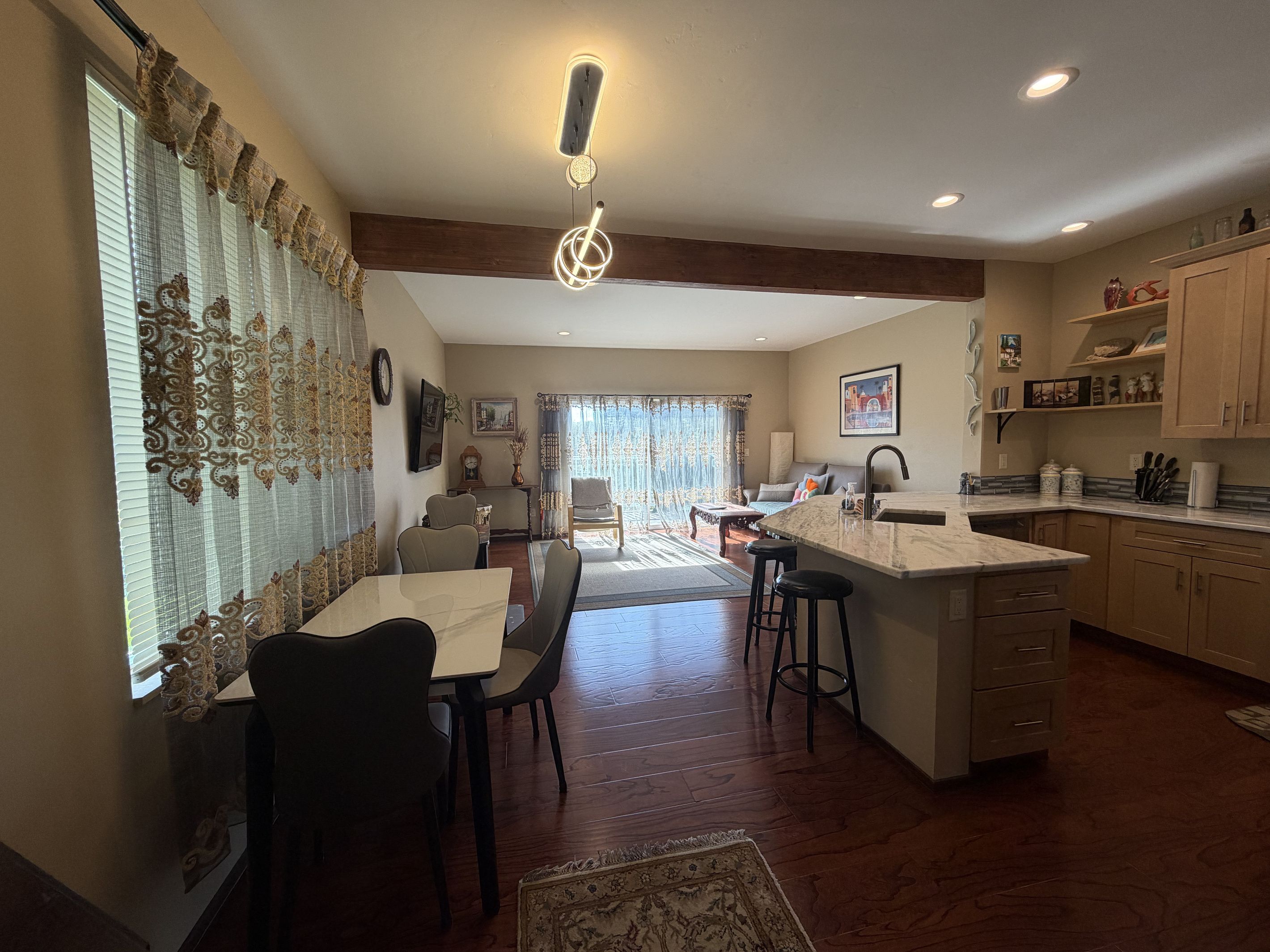 A spacious kitchen with a central island, wooden flooring, and a dining area with chairs and a table.