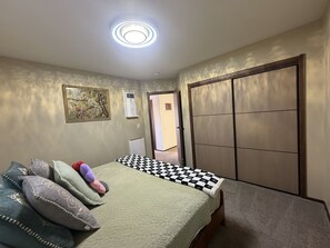 A bedroom with a bed, pillows, a radiator, a window, and a door. - Lake Marie Retreat (East&West) (Rockaway Beach)