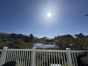 A clear sky with the sun shining, a white fence, and a pond with vegetation. - Lake Marie Retreat (East&West) (Rockaway Beach)