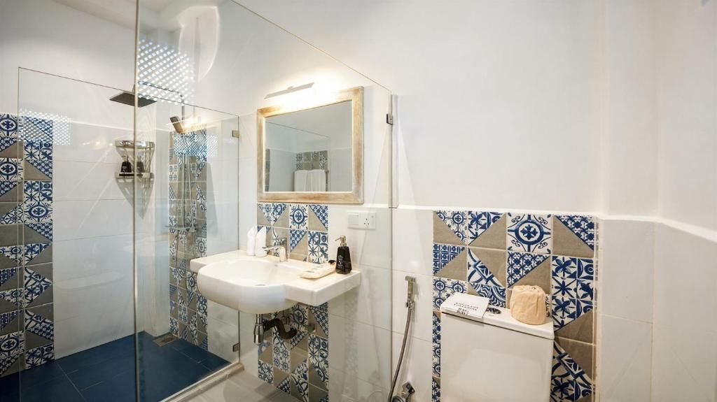 Un baño con ducha de vidrio, lavamanos y espejo.