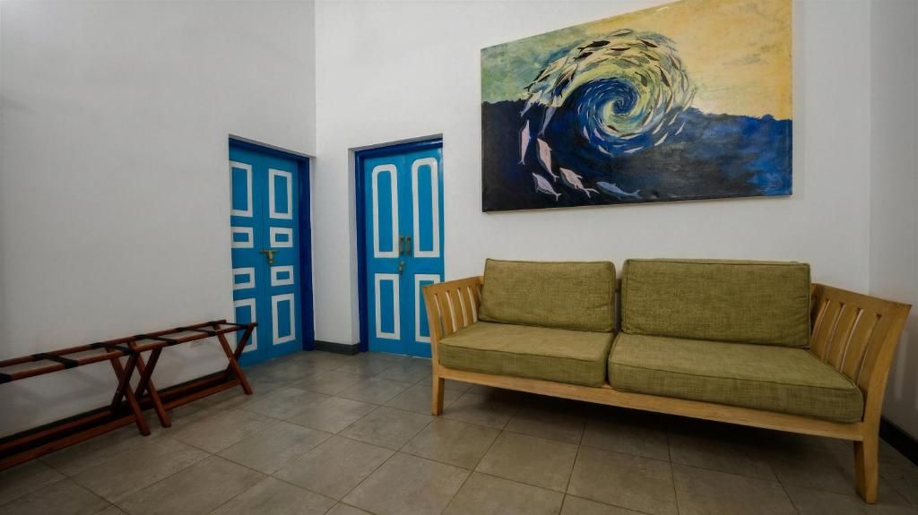 A room with a green sofa, two blue doors, and a painting of a swirling pattern on the wall.