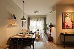 Et moderne spiseområde med et træbord dækket til to personer, en hængende lampe og en sofa i baggrunden.