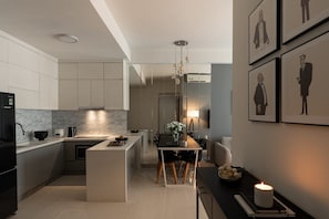 Et moderne køkken med en central ø, et spiseområde med bord og stole, samt en v æg med indrammede kunstværker.