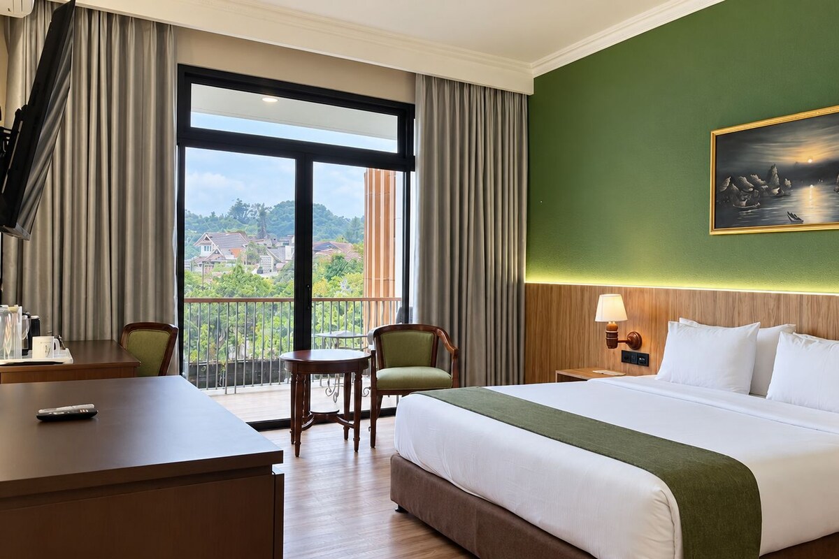 A hotel room with a large bed, a desk, a chair, a nightstand, and a painting on the wall.