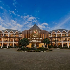 A hotel with a central building featuring a logo and the name 'TULIP PUNCAK RESORT' on the facade.