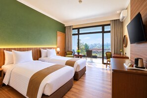 A hotel room with two beds, a desk, a TV, and a balcony with a view.