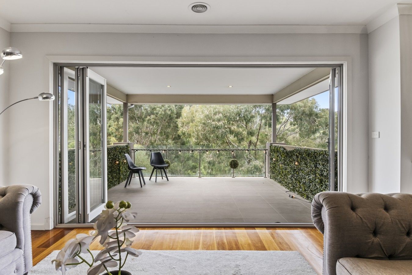 A modern living room with a large sliding glass door leading to an outdoor balcony.