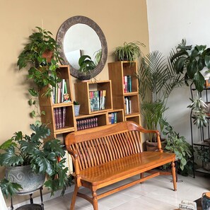 A wooden bench in a room with a bookshelf, a mirror, and various potted plants. - New Listing (Juriquilla)