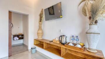 Un pasillo con una consola de madera, un televisor de pantalla plana montado y jarrones decorativos.