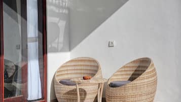Una habitación con dos sillones de mimbre, una mesita y un ventanal corredera.
