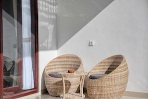 A room with two wicker chairs, a small table, and a sliding glass door.