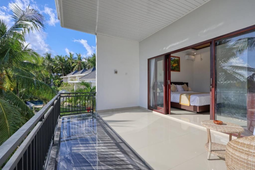 A balcony with a glass door leading to a bedroom with a bed and a small table.