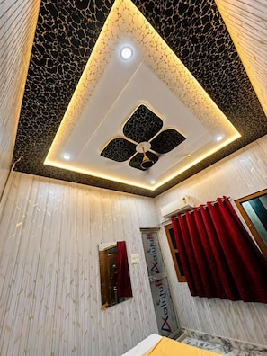 Una habitación con un diseño de techo original, una cama, un ventanal con cortinas rojas y un cartel en la pared.