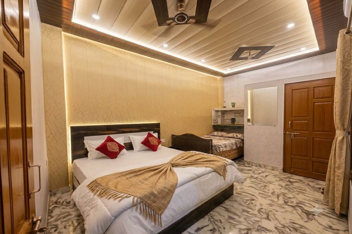 Ein Hotelzimmer mit einem großen Bett, einem Holzkopfstück, einem Marmorboden und einem Deckenventilator.