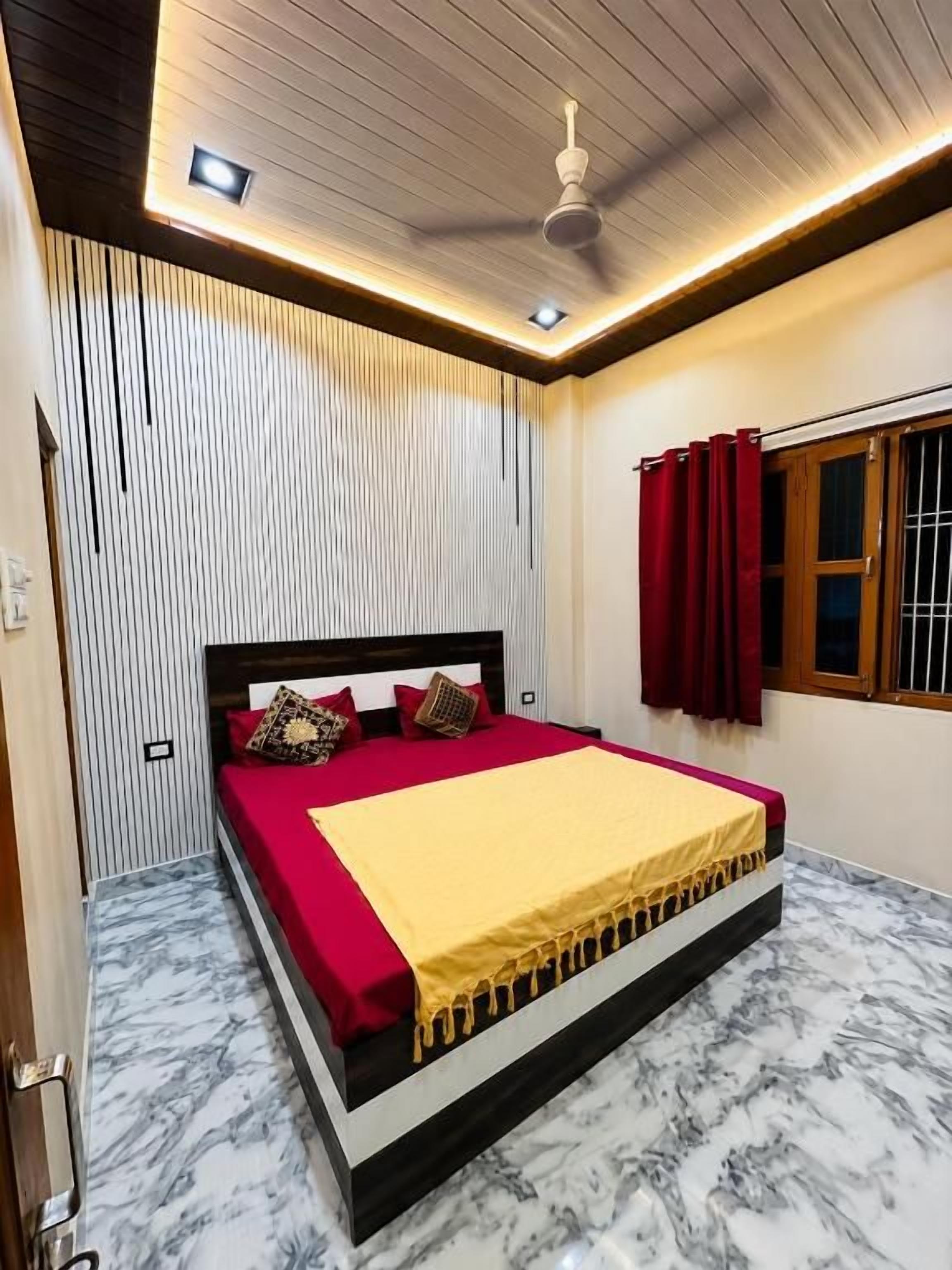 A bedroom with a bed, a ceiling fan, and a window with curtains.