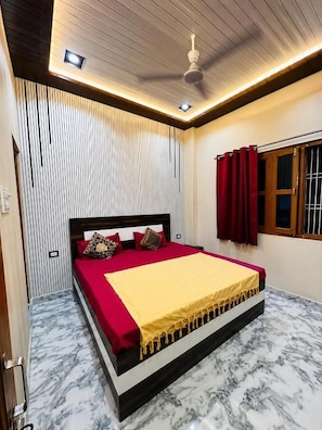 Un dormitorio con cama, ventilador de techo y ventana con cortinas.