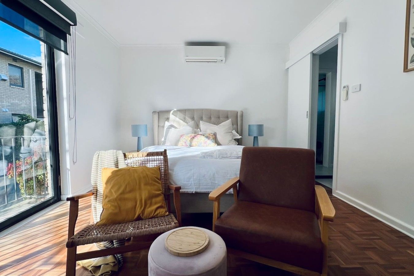A bedroom with a bed, two chairs, a small table, and a window.