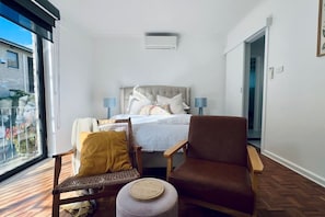 A bedroom with a bed, two chairs, a small table, and a window. - Your stay the feels like home! (Lyons)